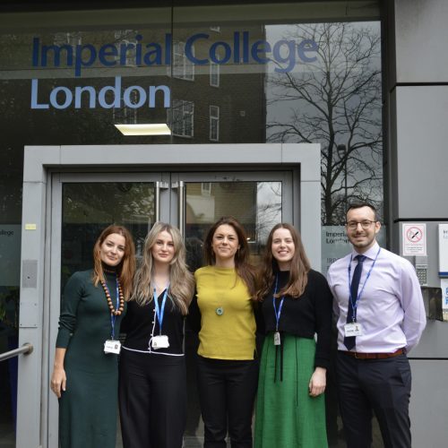Photo of 5 people standing outside a building