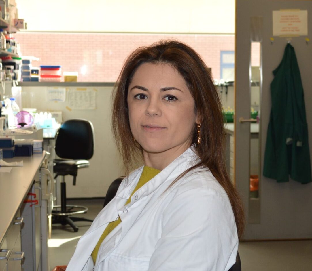 A photo of Maria in her lab coat sat in her lab