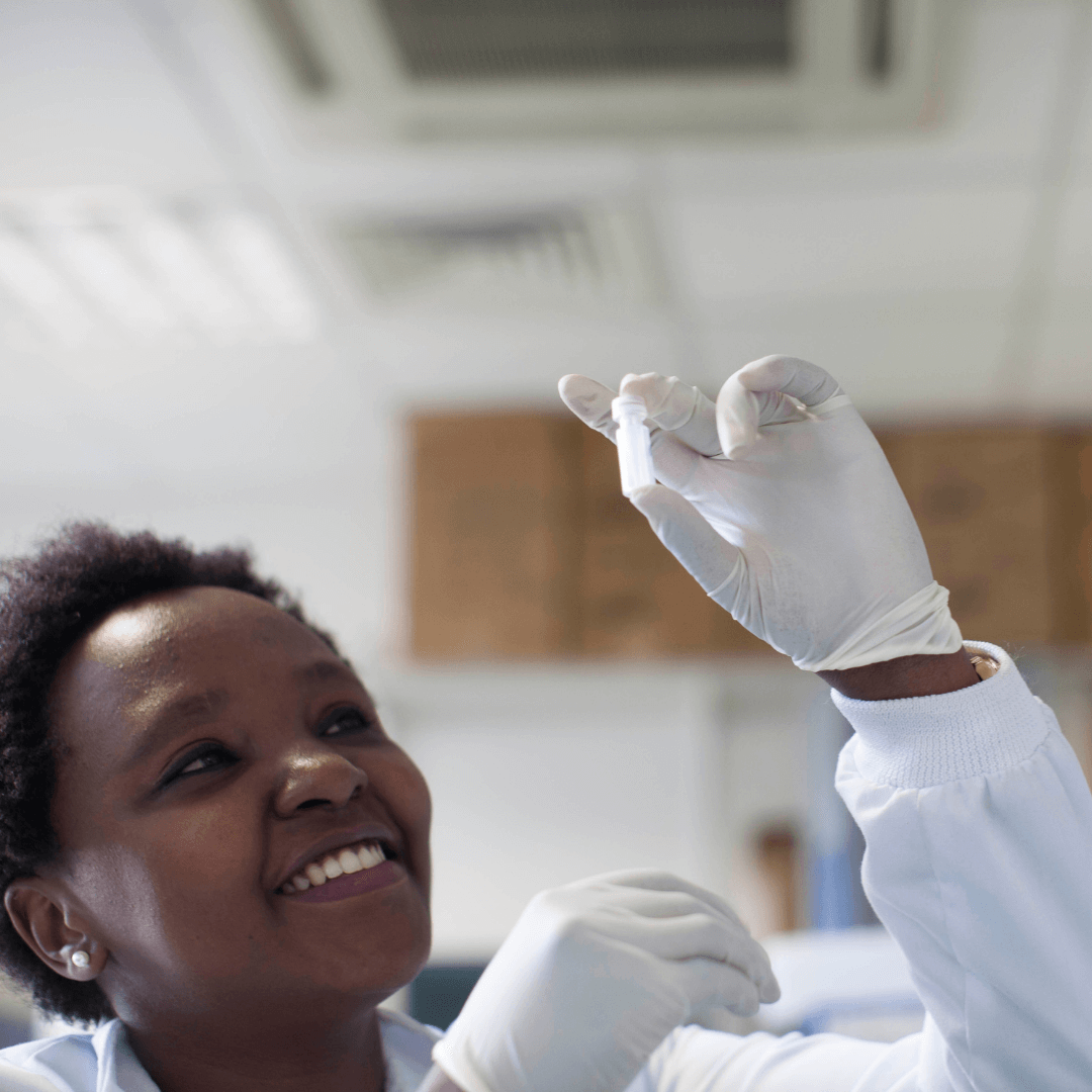 person in a lab with a lab coat wearing gloves